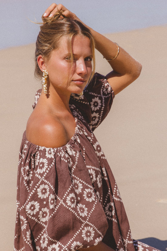Dahlia Maxi Dress Maple — upper body portrait against sand dunes, off-shoulder detail, close-up of hand block print daisy motif on linen | Daughters of India