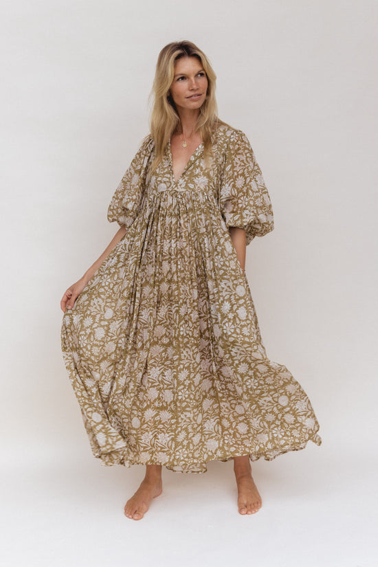 Daughters of India Kyra Maxi Dress in Olive — studio front view holding skirt, V-neckline, flowing hand screen print