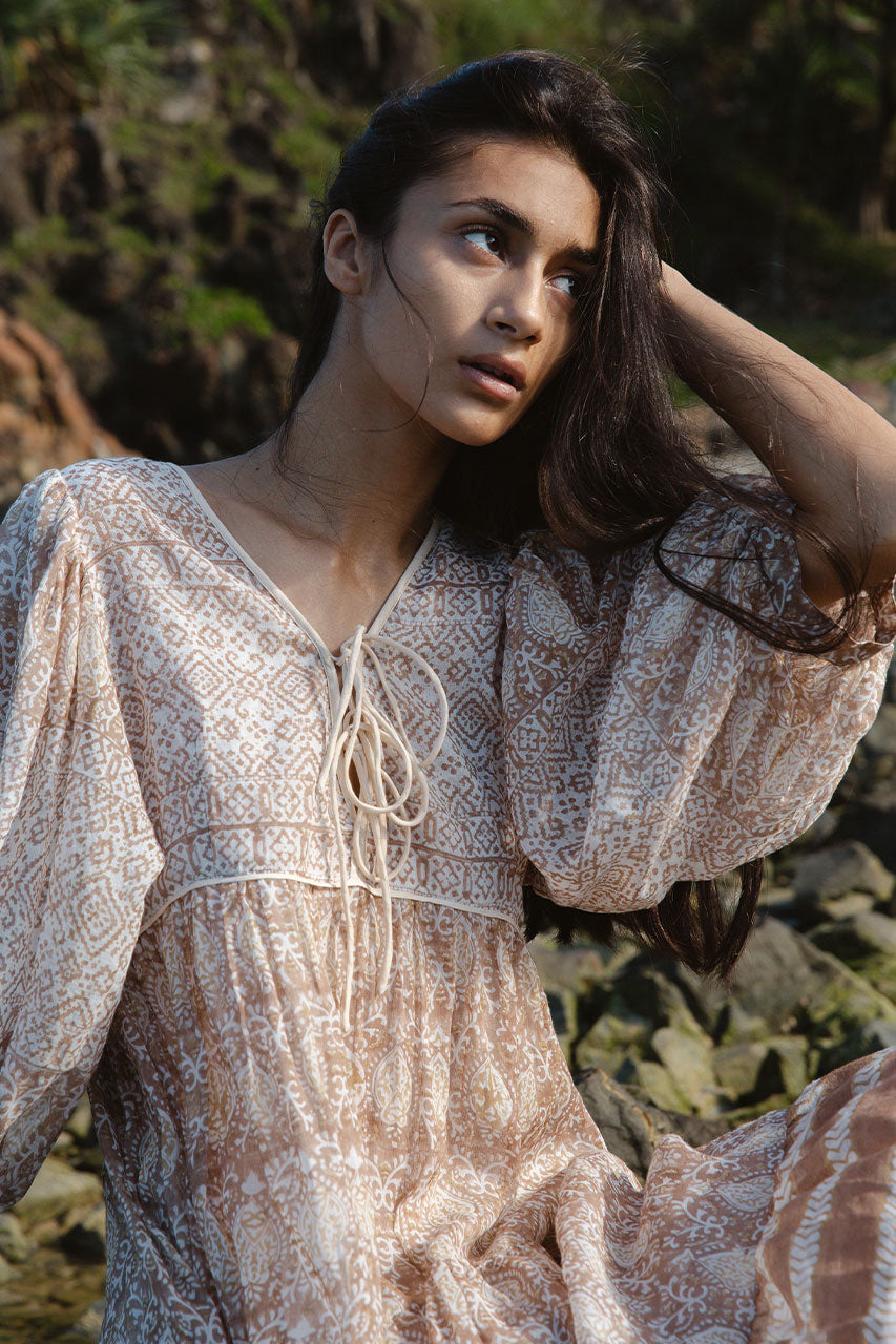 Daughters of India Jasmine Midi Dress in Shell — close-up V-neckline and tie detail seated on rocks in golden light