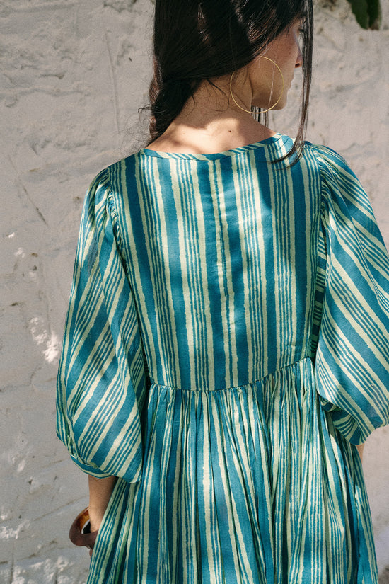 Back detail view of the Daughters of India Kyra Maxi Dress in Spearmint, showing the billowed sleeves and green and white striped cotton fabric with hoop earrings